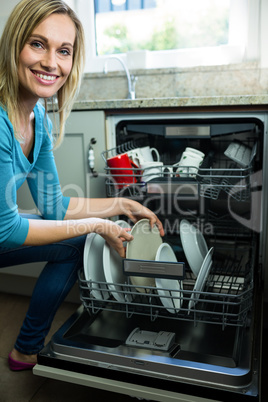 Pretty blonde woman emptying the dishwasher