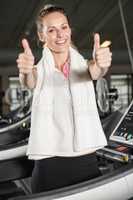 Smiling woman in sportswear showing thumbs up