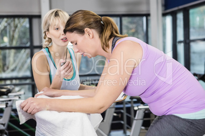 Trainer using stopwatch while pregnant woman is using exercise b