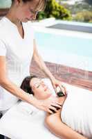 Woman receiving a hot stone massage from masseur