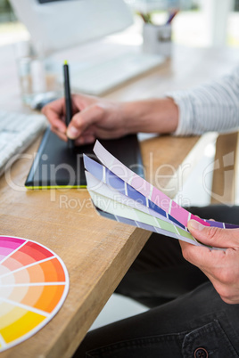 Masculine hands writing on digital tablet about color samples