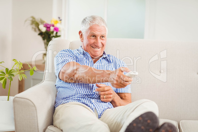 Senior man sitting and watching television at home