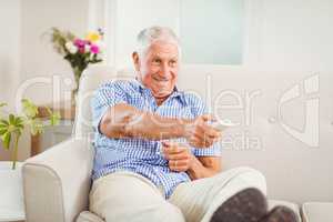 Senior man sitting and watching television at home