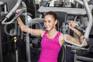 Fit woman using weight machine