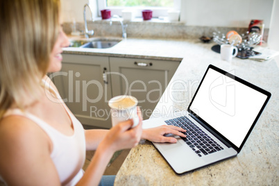 Pretty blonde woman having coffee and using laptop