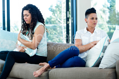 Unhappy lesbian couple sitting on sofa