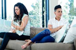 Unhappy lesbian couple sitting on sofa