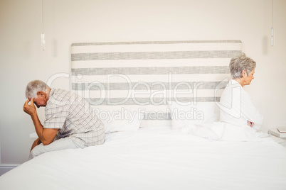 Upset senior couple sitting on the opposite ends of the bed
