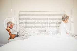 Upset senior couple sitting on the opposite ends of the bed