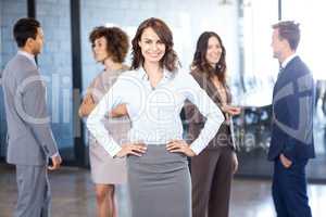 Businesswoman smiling at camera while her colleagues discussing