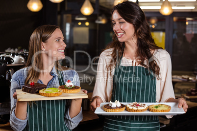 Pretty baristas holding desserts