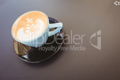 Cup of cappuccino with coffee art on wooden table