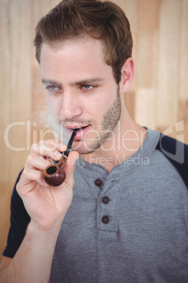 Handsome hipster smoking pipe