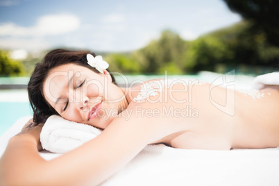 Woman lying on massage table with salt scrub on back