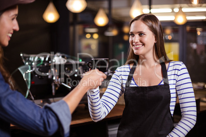 Pretty barista giving coffee to female customer