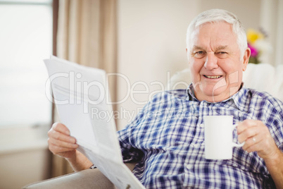 Senior man reading newspaper in living room