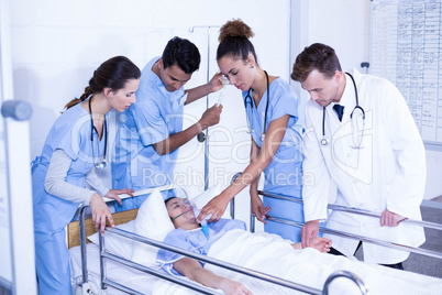 Doctors putting an oxygen mask on patient and adjusting iv drip