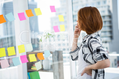 hipster woman staring at notes on thee wall an thinking
