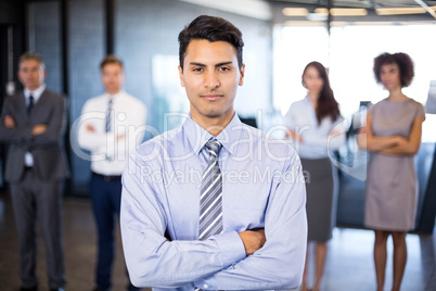 Businessman smiling at camera while her colleagues standing in b