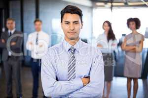 Businessman smiling at camera while her colleagues standing in b