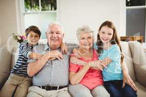 Grandparents and grandchildren sitting together on sofa