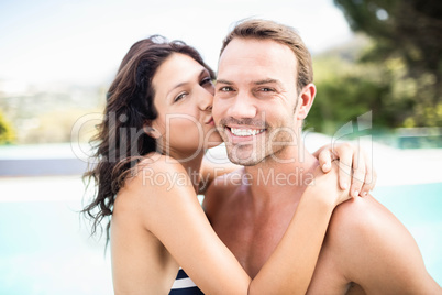 Woman kissing man near pool