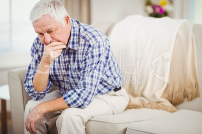 Worried senior man sitting on sofa
