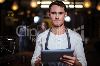 Barista holding tablet and looking at the camera