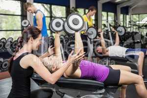 Smiling woman working out with dumbbells with female trainer