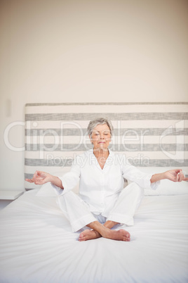 Senior woman meditating on bed