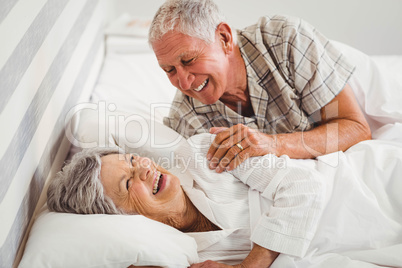 Happy senior couple laughing on bed