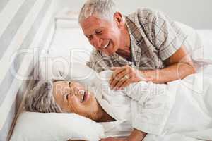 Happy senior couple laughing on bed