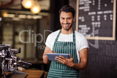 Smiling barista using tablet and looking at the camera