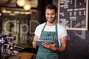 Smiling barista using tablet and looking at the camera