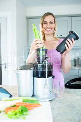 Blonde woman preparing a smoothie in the kitchen