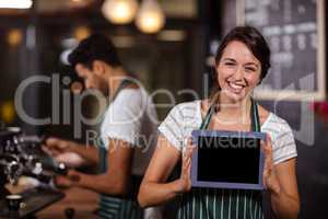 Smiling barista showing tablet at the camera