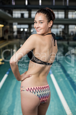 Smiling fit woman in swimsuit with hands on hips