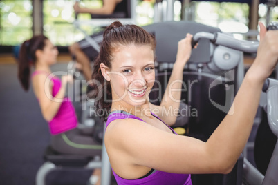 Fit woman using weight machine