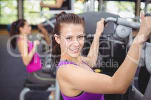 Fit woman using weight machine