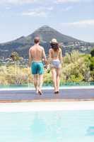 Young couple walking together near pool