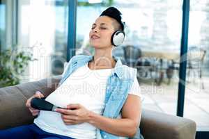 Pregnant woman listening to music on sofa