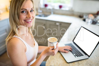 Pretty blonde woman having coffee and using laptop