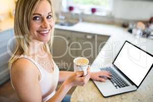 Pretty blonde woman having coffee and using laptop