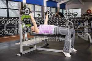 Determined woman lifting barbell