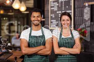 Smiling baristas standing with arms crossed
