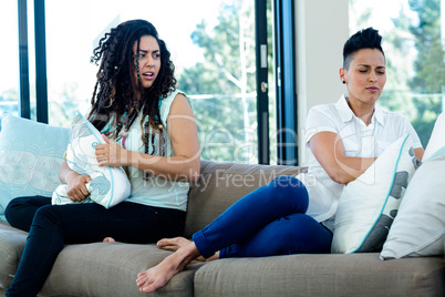 Unhappy lesbian couple sitting on sofa