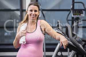 Smiling pregnant woman standing next to exercise bike