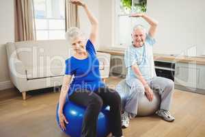 Senior couple doing stretching exercise on exercise ball