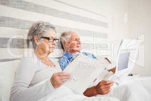 Senior woman reading magazine and senior man reading newspaper