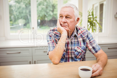 Thoughtful senior man sitting at table